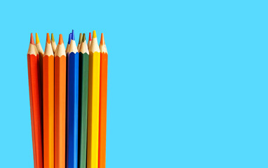 Colored pencils grouped together on a blue background with copy space. 