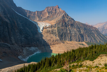 Incredible nature views at Edith Cavell glacier in Jasper Banff National Park in Canadian Rockies during summer time with stunning glacial lake and ice chunks covering the rocky mountain terrain land - obrazy, fototapety, plakaty