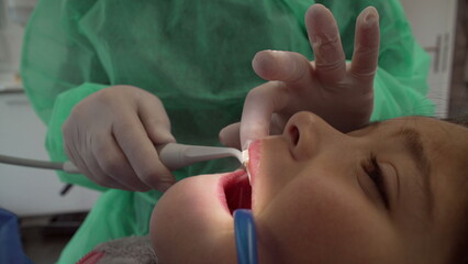 Dentist treating child's teeths at dental clinic. Healthcare workforce of female doctor taking care of patient's oral hygiene