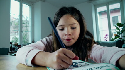 Focused Young Girl Drawing Creatively on Paper. A little girl deeply engaged in artistic play,...