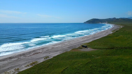 Panoramic aerial shot of a sunny coastal landscape in Spain. Clip. Green meadow highlands and sea...