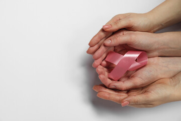Breast cancer awareness. Women holding pink ribbon on white background, top view. Space for text