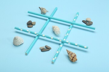 Tic tac toe game made with sea treasures on light blue background