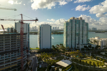 Fototapeta premium Aerial view of new developing residense in american urban area. Tower cranes at industrial construction site in Miami, Florida. Concept of housing growth in the USA