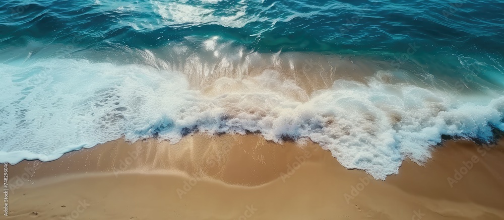Poster this aerial view showcases a sandy beach with waves rolling in from the ocean, breaking onto the sho