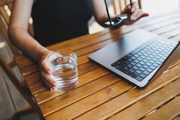 A glass of water on the background of a laptop on a summer terrace. Work in a cafe. Remote work online.
