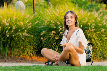 Młoda uśmiechnięta dziewczyna siedzi na trawniku w ogrodzie
