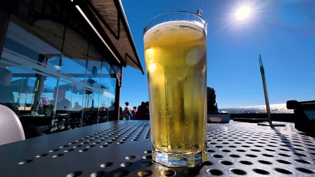 a glass of beer on a table in a cafe on the terrace against the background of the sky and sea