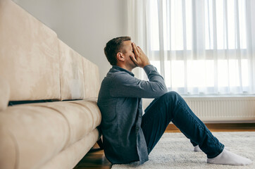 A depressed man is sitting on the floor in despair.