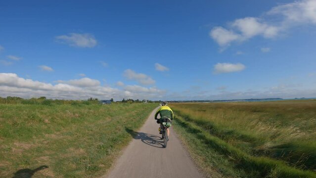 POV view of two cyclist rides on gravel bike path next to ocean in north of france region normandy towards Mont Saint-Michel. France cycling theme. Walking path and bike on beach of region Bretagne