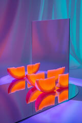 An artistic composition with vivid orange slices symmetrically arranged and reflected on a mirrored surface.
