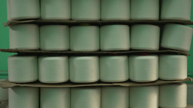 Stacks of Thread Spools in Textile Factory. Rows of pale green thread spools on warehouse shelves.