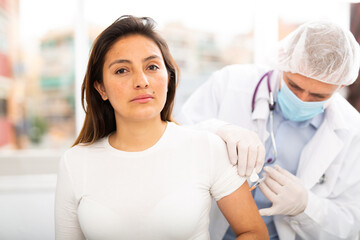 Fototapeta premium Health care concept, doctor in protective face mask vaccinates woman against coronavirus at vaccination center