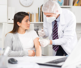 Doctor giving Covid-19 or flu antivirus vaccine shot to patient wear face mask protection at...