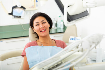 Portrait of a satisfied asian woman patient sitting in a dental chair in the clinic office