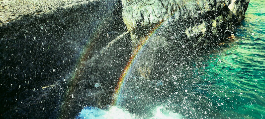 A rainbow emerges when it rains. rainbow with splashing water of a sea. Art of Nature Rainbow in water droplets.