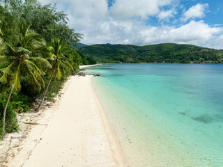 Coconut trees in white sandy beach with waves. Romblon Island. Romblon, Philippines.