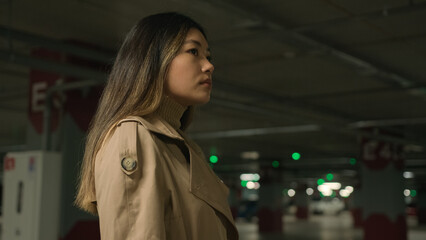 Asian chinese woman korean japanese businesswoman driver confident looking in side look away thoughtful pensive ethnic girl stand alone wait taxi in city parking underground female portrait side view