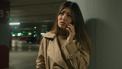Anxious upset Asian woman chinese korean girl japanese businesswoman talk mobile phone outside car...
