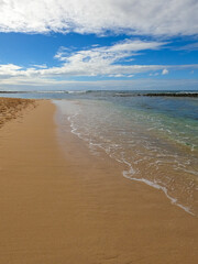 Tropical shoreline where blue ocean water meets sandy beach under a blue sky - 748338220
