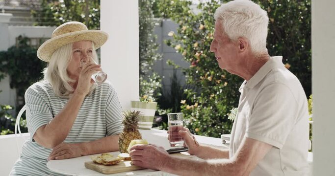 Old couple, glass and drinking or cheers happy in garden for retirement connection, talking or pineapple snack. Man, woman and elderly marriage on porch in conversation for cool beverage, love or sun