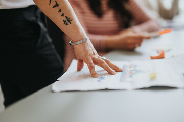 Focused shot capturing the hands of a diverse team collaborating over business charts and documents on a white desk. - obrazy, fototapety, plakaty
