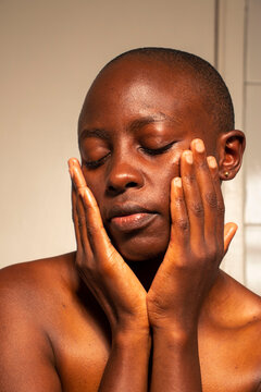 Portrait of a young black woman massaging her face