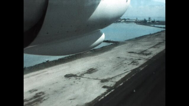 Landing at Tahiti International Airport 1971 - Viewed from the cabin, the approach and landing of an airplane at Tahiti International Airport focuses on the portside engine and landing gear, in 1971.