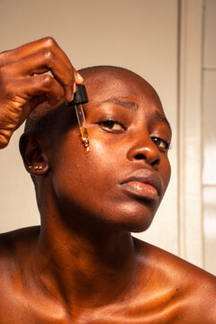 Woman applying oil on her face