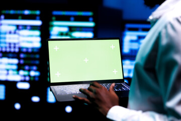 Computer scientist using green screen laptop to verify configuration settings of data center...