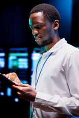 African american admin using laptop to review energy consumption across server rack parts....