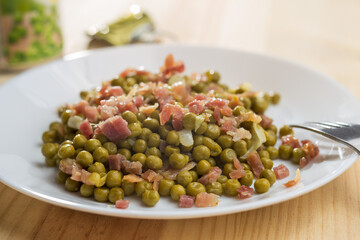 Dish of peas with ham and chives served on a white plate.