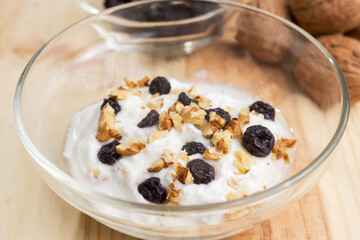 Natural sugar-free yogurt dessert accompanied by blueberries and walnuts served in a glass bowl.