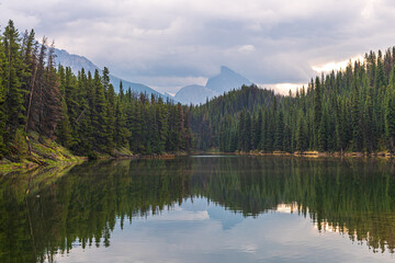 Moose Lake Loop Hike at Maligne Lake during fall, autumn September on cloudy day with reflection in clam water below stunning Canadian landscape scene. 
