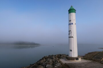 Lac du Der Chantecoq, en Champagne Ardenne, dans la région Grand Est, paysage avec le phare du port de Nemours dans la brume à l’aube (France)