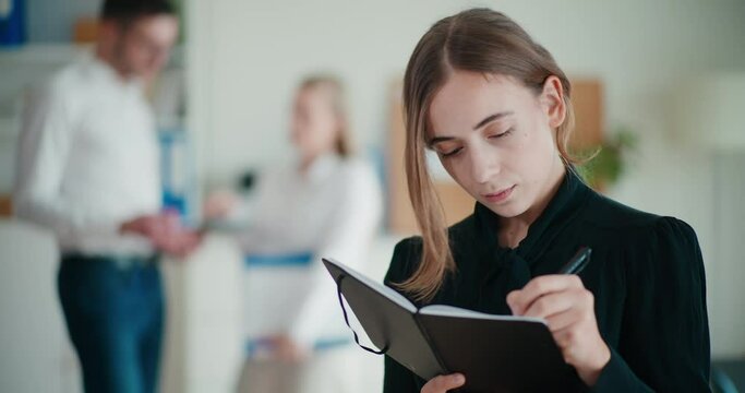 Young businesswoman writing strategy in diary