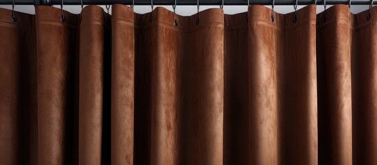 A detailed view of a brown fabric curtain hanging from a sturdy metal rod, adding a touch of elegance to the room decor.