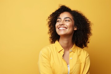 Beautiful african american woman smiling and looking away over yellow background