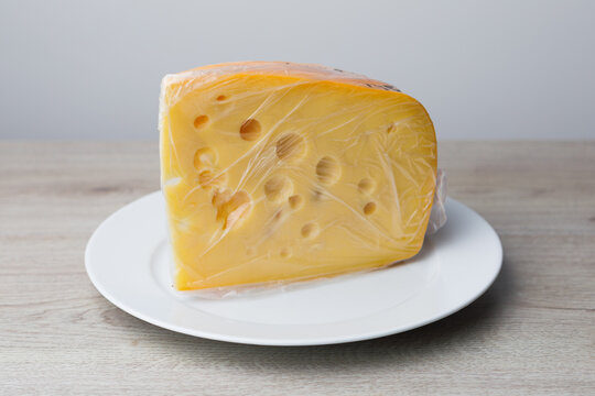 maasdam cheese on a plate, grey background