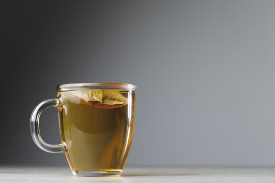 herbal tea in transparent cup on grey background with copy-space
