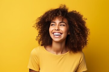 Portrait of a beautiful young african american woman laughing over yellow background