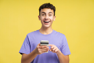 Fototapeta premium Portrait of amazed teenager wearing braces holding mobile phone, using website, looking at camera