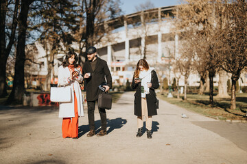 Three business professionals engaged in an informal meeting while taking a walk on a sunny winter day in an urban park setting.