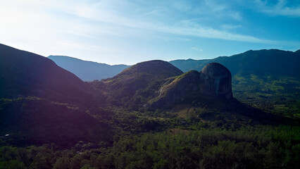 A breathtaking aerial perspective captures a vast mountain range stretching into the horizon, with lush trees dotting the landscape. The unparalleled beauty of nature unfolds in this panoramic view.