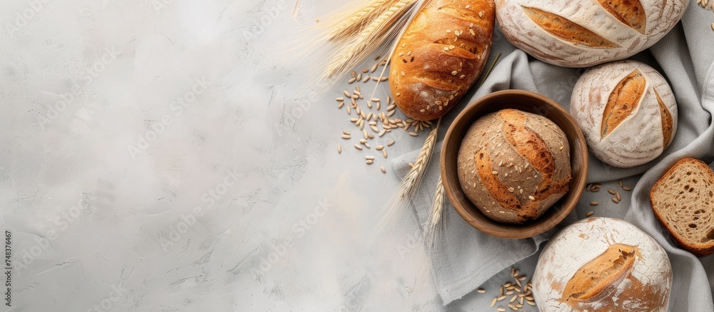 Poster a variety of multigrain rustic bread loaves are displayed on a table with kitchen towels in a top-do