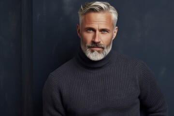 Handsome middle-aged man with gray hair and beard wearing a sweater.