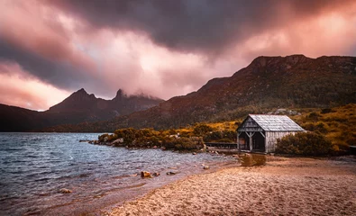 Papier Peint photo Mont Cradle The view of the Dove Lake Boatshed and the Cradle Mountain under the rosy clouds in the dusk