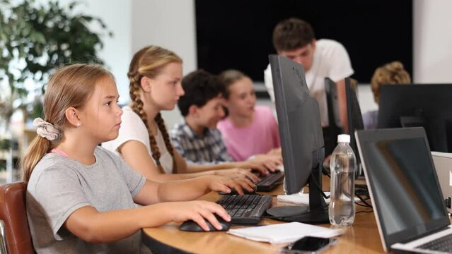 Curious underage girl engaged in IT training during computer courses for children