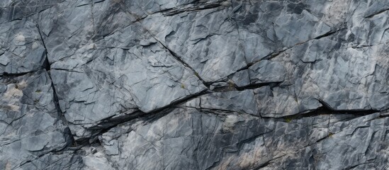 An elevated view of a grey, rugged granite stone surface forming a rock wall. The black and white image highlights the texture and shape of the rocks.