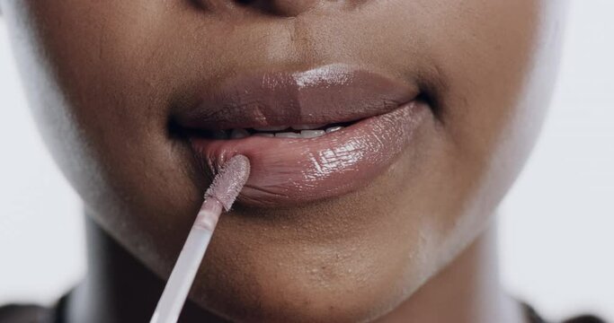 Makeup, lip gloss and closeup of black woman on a white background for cosmetics, products and shine. Beauty, mouth and lips of isolated person with lipstick for wellness, glow or aesthetic in studio